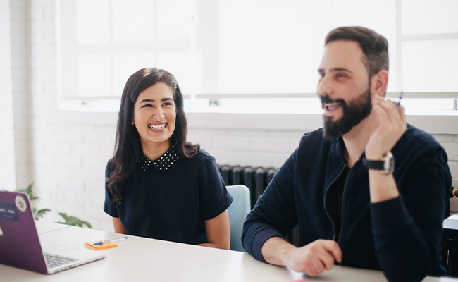Two people sitting in a work space talking